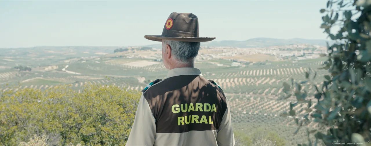 Still from Bañeras: a Guarda Rural warden in a wide-brimmed hat looks out over olive groves in southern Spain.