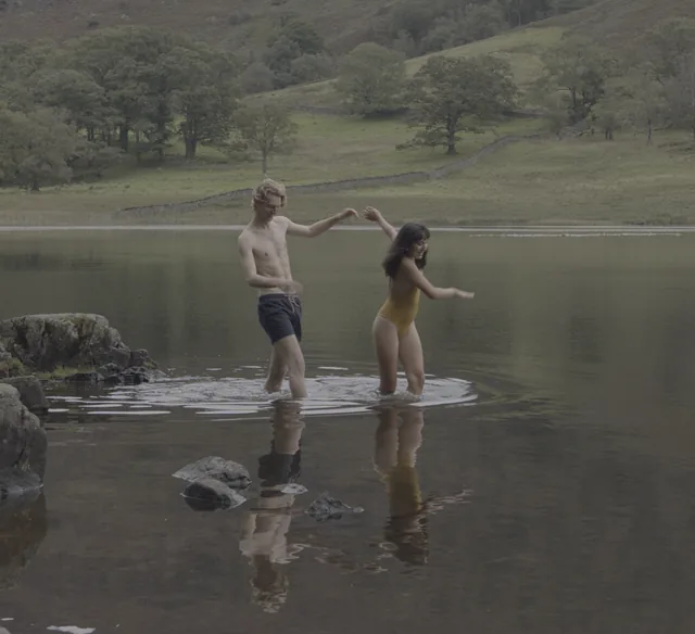 Ethan and Sam dance in the shallows of a lake at dusk.